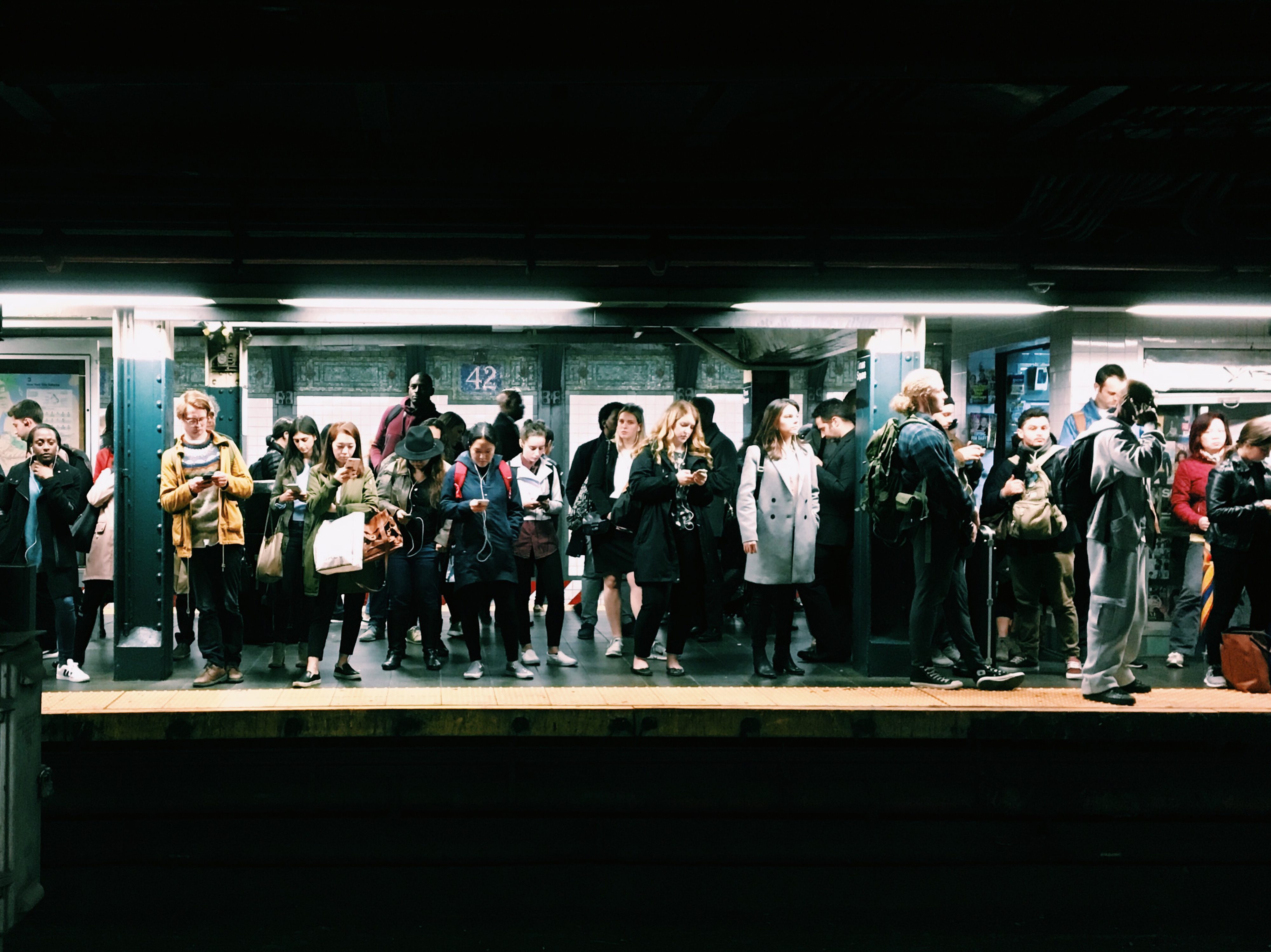 A large crowd standing on the subway platform in Times Square, Manhattan.